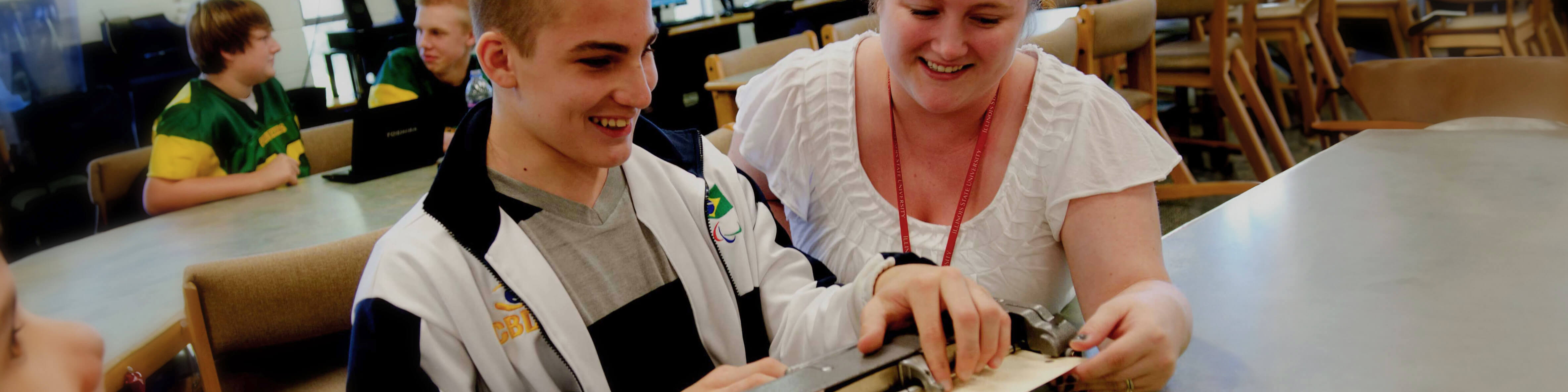 Teacher helping student using a braille machine.