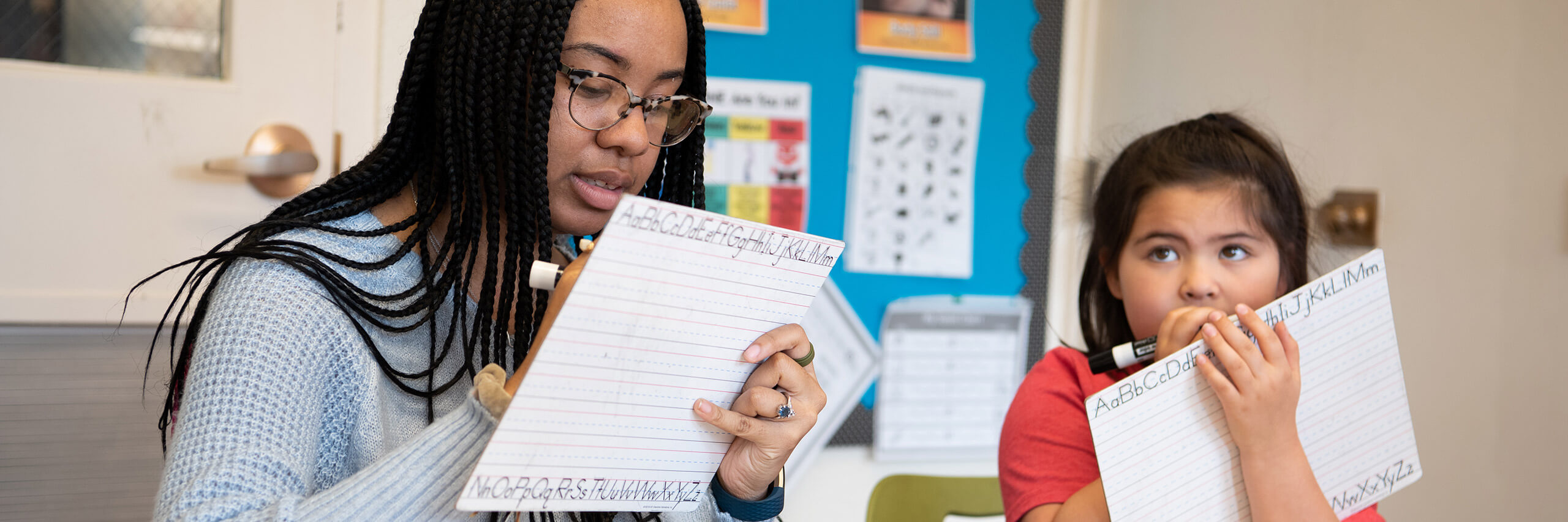 A teacher and student collaboratively writing on a piece of paper, engaged in a learning activity.