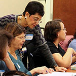 Adult students working in a classroom with a professor.