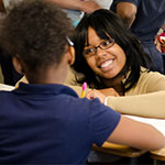 Female college student smiling at elementary student.